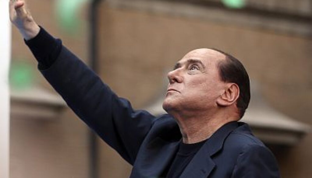 Former Italian Prime Minister Silvio Berlusconi waves during a rally to protest his tax fraud conviction, outside his palace in central Rome