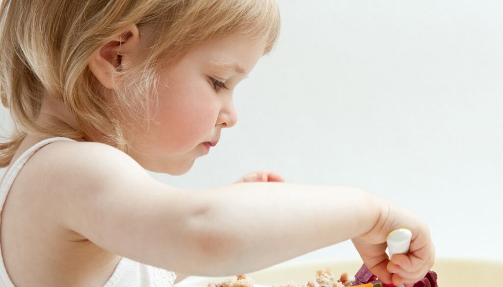 Adorable baby girl eating fresh vegetables