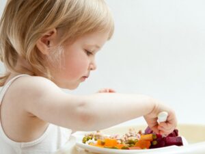Adorable baby girl eating fresh vegetables